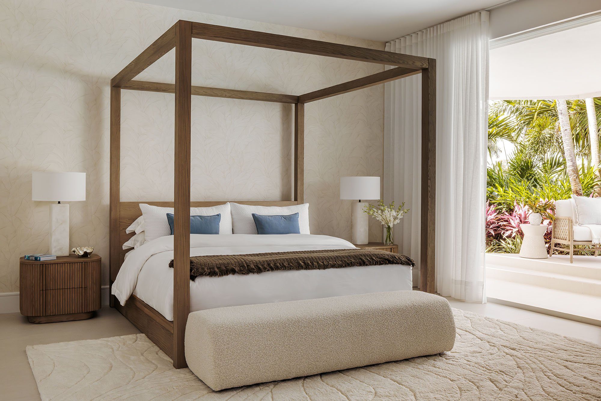 Serene primary bedroom with a wood canopy bed and tropical garden view