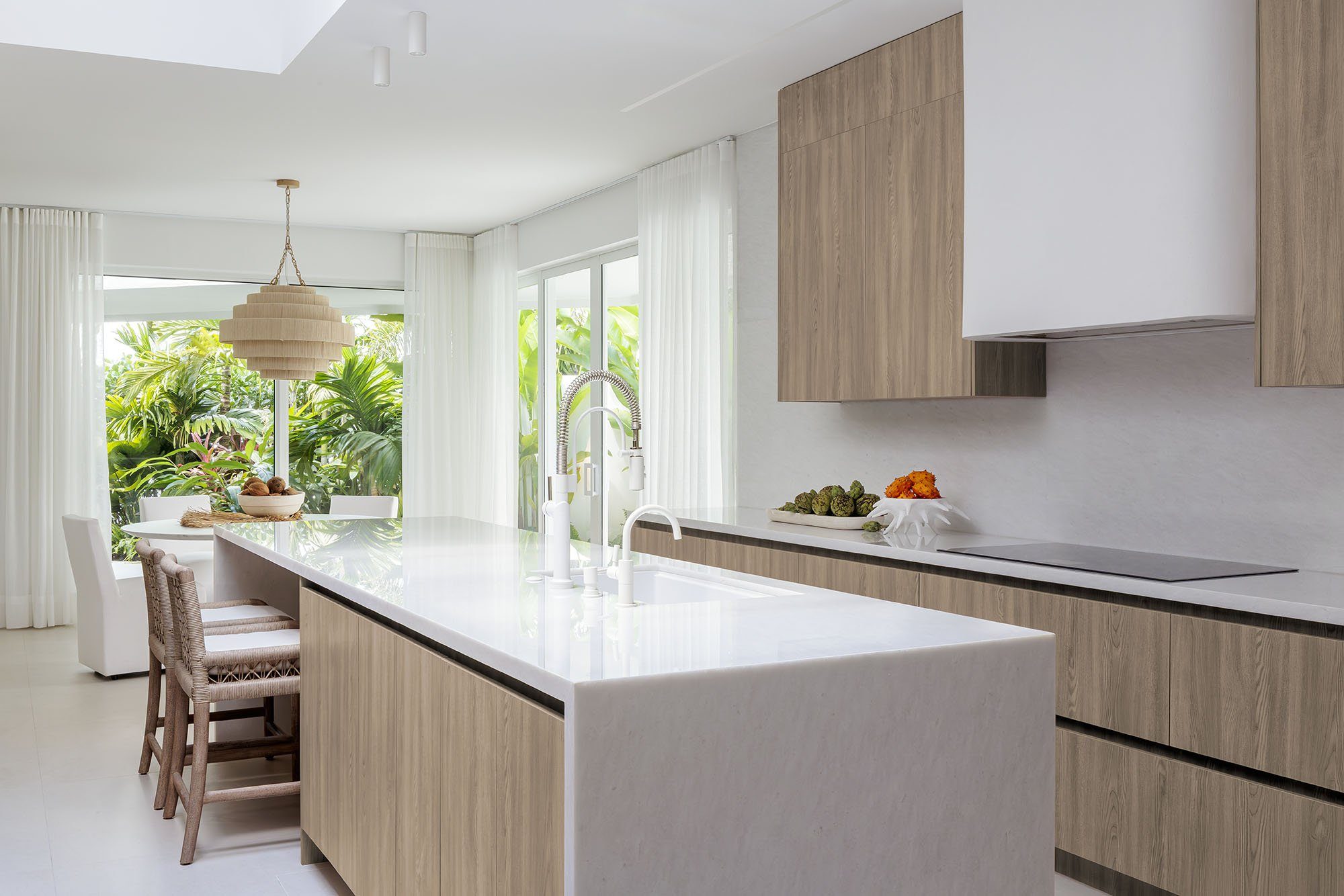 Bright modern kitchen with a marble island and tropical garden view